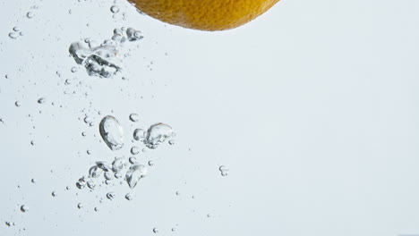 Closeup-tropical-orange-falling-water-in-light-background.-Fresh-summer-fruit