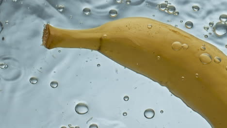 Closeup-fresh-banana-water-floating-in-light-background.-Yellow-tropical-fruit