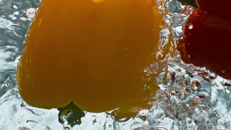 Two-peppers-splashing-water-closeup.-Organic-colorful-paprika-bouncing-floating