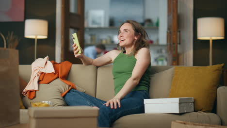 Happy-woman-using-smartphone-at-sofa.-Overjoyed-shopaholic-rejoicing-emotionally