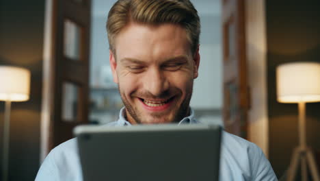 Inspired-businessman-reading-tab-home-zoom-on.-Laughing-man-tablet-funny-video