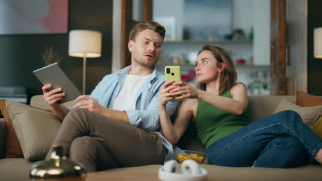 Serious-woman-showing-mobile-phone-to-boyfriend.-Involved-spouses-using-devices
