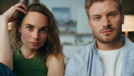 Focused-pair-staring-tv-show-at-home-closeup.-Man-hand-holding-remote-controller