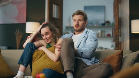 Frightened-spouses-watching-tv-sitting-at-evening.-Couple-enjoying-scary-movie