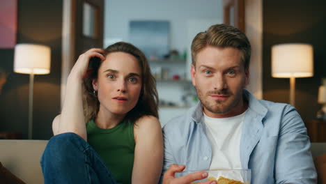 Amazed-partners-enjoying-tv-show-indoor-closeup.-Relaxed-lovers-discussing-movie