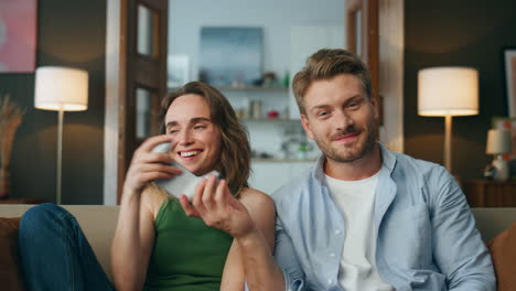 Smiling-man-giving-gamepad-to-wife-at-home-pov.-Laughing-woman-taking-joystick