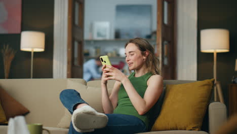 Mujer-Riendo-Charlando-Con-El-Celular-En-Casa.-Señora-Sonriente-Leyendo-Un-Mensaje-Divertido