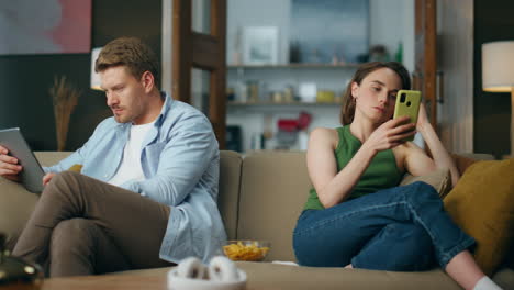 Involved-couple-reading-devices-at-room.-Internet-addicted-family-using-gadgets