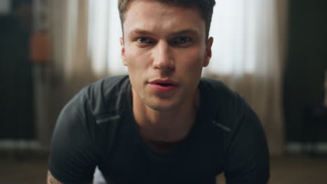 Young-sportsman-training-home-close-up.-Man-standing-on-knees-making-exercise.