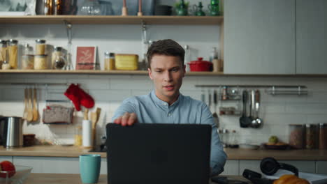 Man-finish-online-meeting-closing-laptop-drinking-coffee-at-kitchen-close-up.