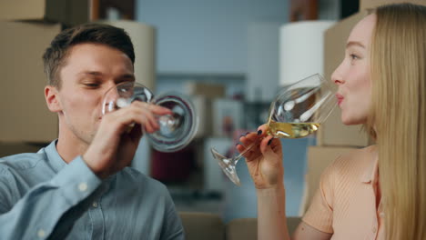 Happy-couple-celebrating-moving-into-new-house-drinking-wine-near-boxes-close-up