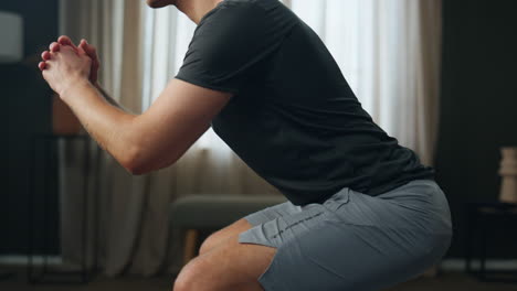 Sporty-man-exercising-room-close-up.-Athletic-guy-making-squats-in-sportswear.