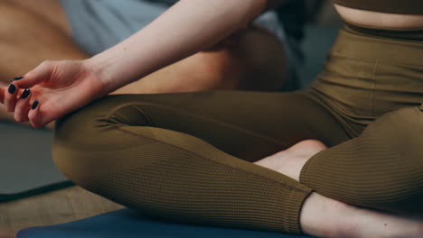 Woman-sitting-lotus-position-with-crossed-legs-on-mat-close-up.-Girl-meditating.