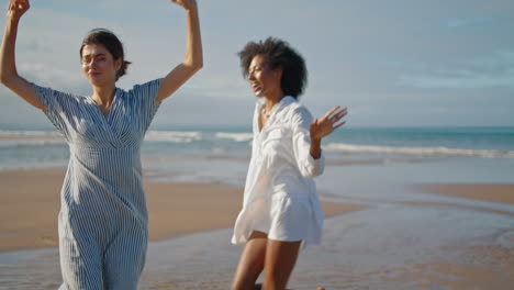 Fröhliche-Mädchen-Tanzen-Am-Sommerwochenende-Am-Strand.-Aufgeregt-Lächelndes-LGBT-Paar-Genießt