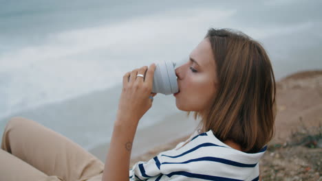 Girl-drinking-coffee-ocean-view-vertical-closeup.-Relaxed-tourist-resting-cliff
