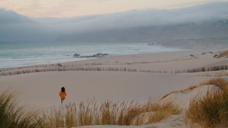 Mädchen-Läuft-Am-Sandstrand,-Düsterer-Abend-In-Der-Ferne.-Frau-Joggt-Am-Leeren-Strand