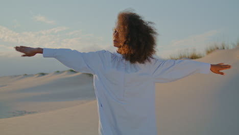 Focused-woman-dancing-modern-style-on-sandy-desert-at-summer-windy-evening.