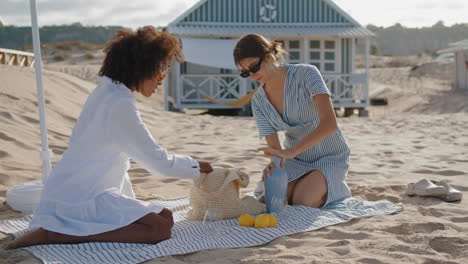 Mujeres-Homosexuales-Descansando-En-La-Playa-En-La-Mañana-De-Verano.-Dos-Amigos-Disfrutando-De-Un-Picnic