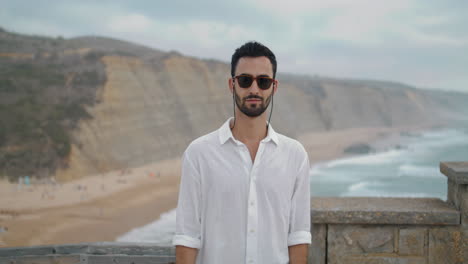 Man-model-looking-camera-on-sea-beach.-Smiling-guy-posing-seashore-portrait.