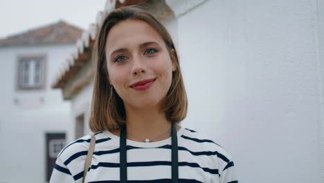 Portrait-beautiful-girl-tourist-posing-at-white-town-buildings-vertically-shot.