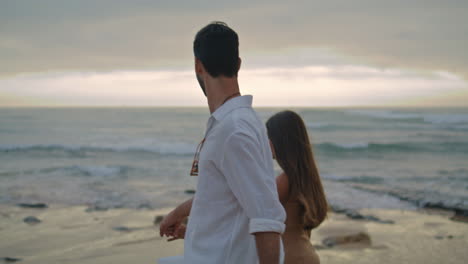 Lovely-family-holding-hands-at-misty-ocean-closeup.-Young-couple-walking-beach