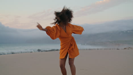 Contemporary-dancer-waving-hands-performing-on-sand-seashore-summer-evening.