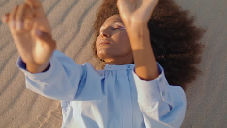 Woman-performer-lying-sand-dune-making-smooth-hands-movements-close-up.