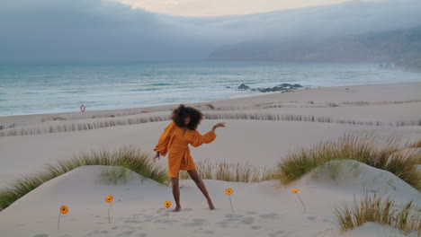 Woman-moving-gracefully-beach-near-orange-flowers-gloomy-evening.-Girl-dancing.