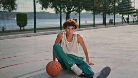 Curly-sportsman-sitting-stadium-zoom-on.-Basketball-player-relaxing-portrait