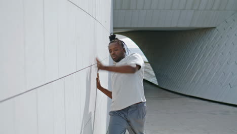 Enthusiastic-man-dancing-wall-rhythmically-vertical-view.-Modern-guy-performing