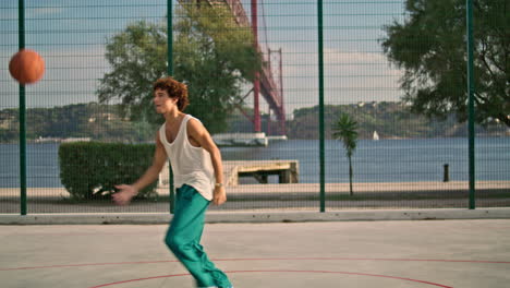 Chico-Rizado-Jugando-Baloncesto-En-El-Campo-De-Deportes.-Adolescente-Lanzando-Pelota-Verticalmente