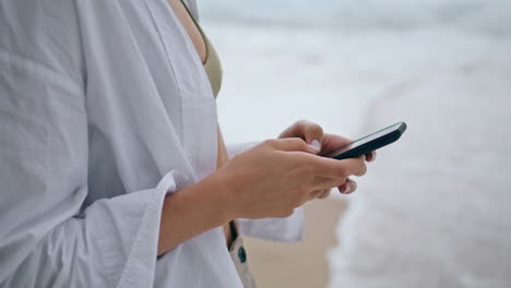 Young-girl-answering-phone-call-on-cloudy-beach-close-up.-Woman-using-telephone