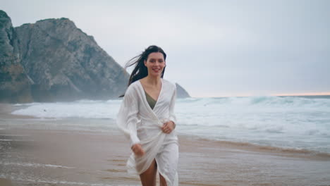 Chica-Serena-Corriendo-En-La-Playa-Del-Océano-En-Un-Día-Nublado.-Mujer-Trotando-Olas-Verticalmente