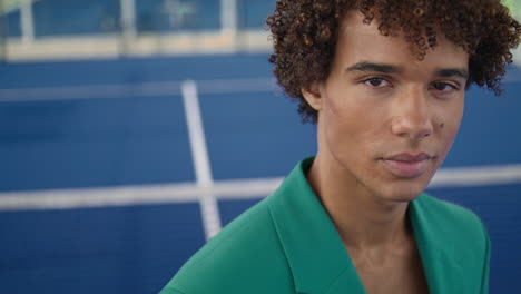 Curly-teenager-looking-lens-stadium-background-portrait.-Serious-model-posing