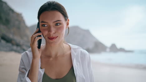 Portrait-woman-calling-walking-seashore.-Girl-talking-phone-on-beach-vertically