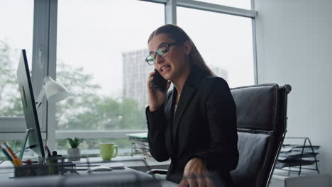 Financial-advisor-talking-smartphone-in-office.-Confident-businesswoman-working