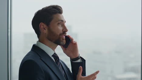 Office-worker-talking-phone-laughing-at-window.-Man-hearing-good-news-close-up.