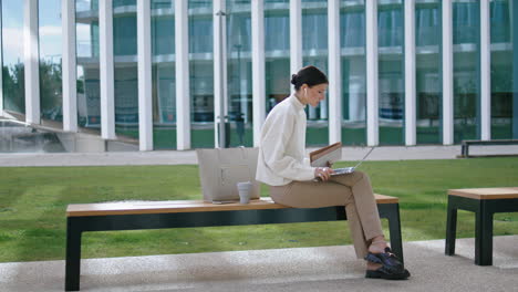 Mujer-Hablando-Video-Chat-Portátil-Sentado-En-Un-Banco-Al-Aire-Libre.-Chica-Realizando-Un-Seminario-Web.