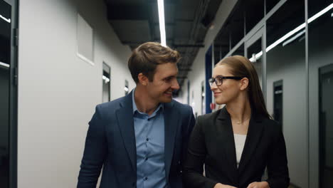 Two-employees-walking-office-together.-Smiling-specialists-going-client-meeting