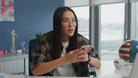 Mujer-Alegre-Mensajería-Smartphone-Oficina-Primer-Plano.-Niña-Sonriente-Respondiendo-Correo-Electrónico