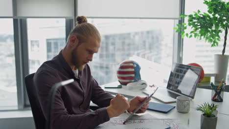 Involved-artist-creating-tablet-at-office-close-up.-Young-man-using-laptop