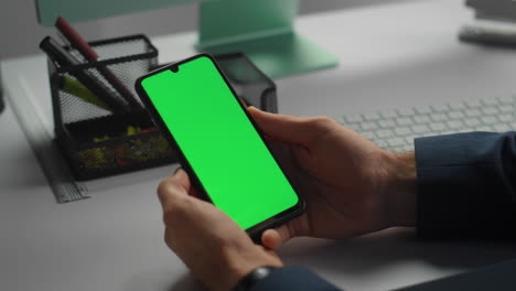 Hands-holding-green-smartphone-closeup.-Office-employee-checking-stock-market