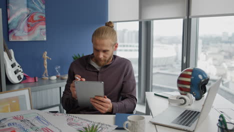 Talentierter-Künstler,-Der-Im-Büro-Aus-Nächster-Nähe-Mit-Dem-Tablet-Skizziert.-Inspirierter-Mann,-Der-Mit-Einem-Zeichenstift-Zeichnet