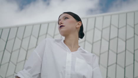 Model-posing-futuristic-building-cloudy-day-close-up.-Portrait-lady-vertical