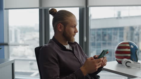 Thinking-man-checking-mobile-at-hipster-room-closeup.-Manager-creating-message