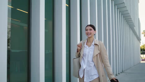 Woman-tourist-talking-phone-on-city-walk-using-wireless-headphones-vertically