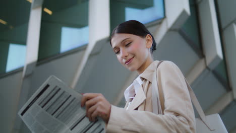 Business-woman-holding-newspaper-standing-in-front-modern-building-close-up.