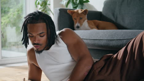 Modern-artist-posing-camera-at-apartment-portrait.-Dog-resting-sofa-closeup