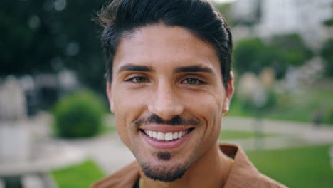 Smiling-man-looking-camera-in-nature-vertically-portrait.-Cheerful-latin-guy