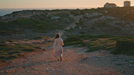 Feliz-Turista-Caminando-Por-La-Orilla-Del-Océano-Al-Atardecer.-Mujer-Alegre-Paseando-Por-El-Camino